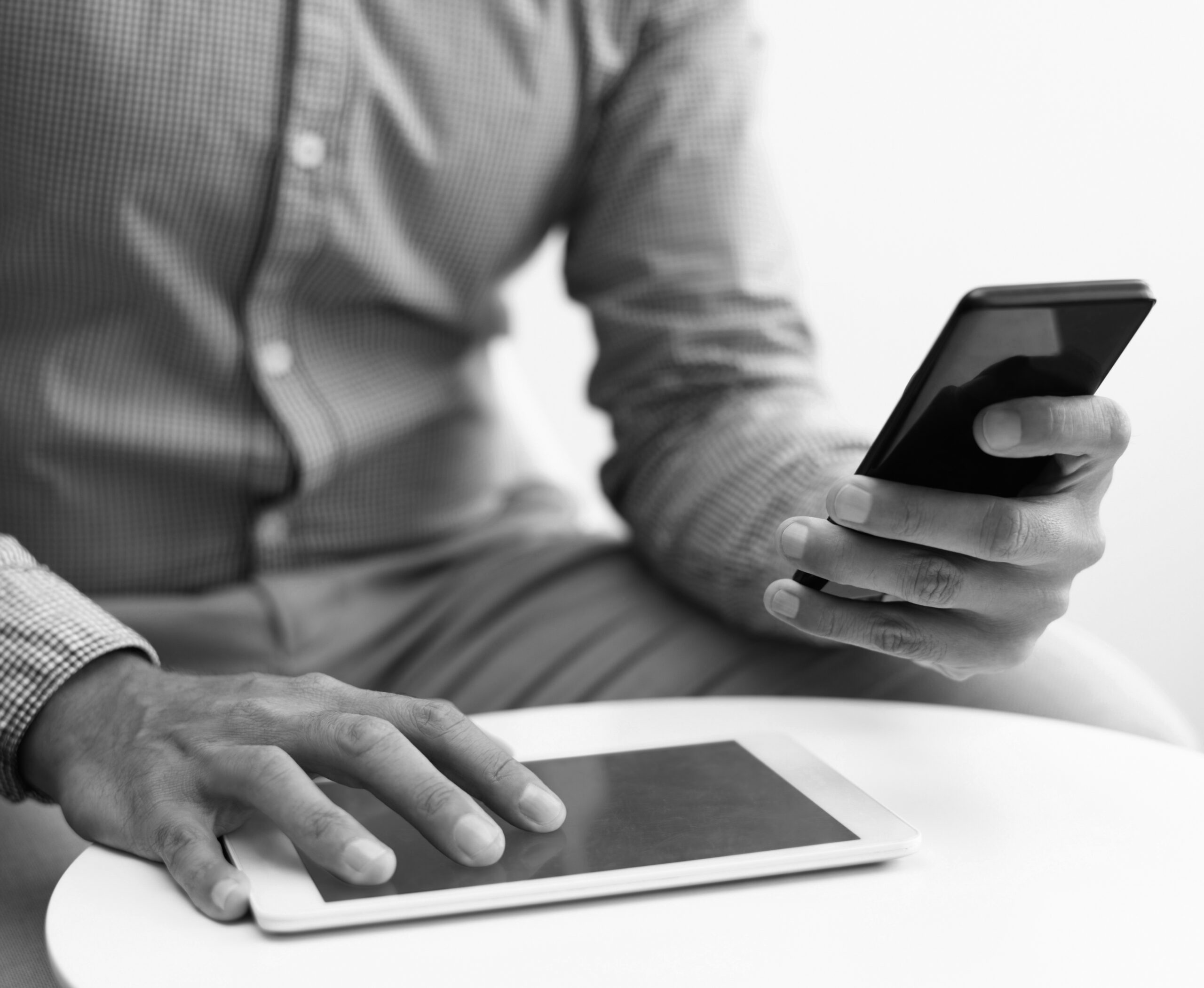 Closeup of man using smartphone and tablet at coffee table. Business man using digital devices. Technology and communication concept. Cropped view.